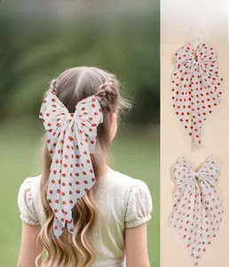 Detail of large bow hair clip with fresh strawberry pattern on soft white fabric