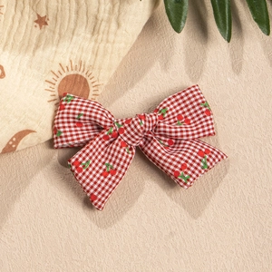 Detailed view of red plaid bow hair clip with cute cherry patterns for children