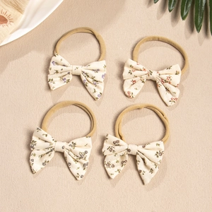 Close-up of four floral print bow headbands with soft nylon elastic for infants