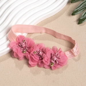 Detail eines rosa elastischen Stirnbandes mit drei handgemachten 3D-Stoffblumen für Babys