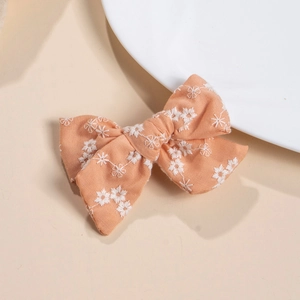 Close-up of pink cotton fabric hair clip featuring delicate white floral embroidery details