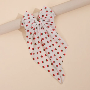 Detail of white floral hair bow featuring red strawberry patterns on soft chiffon fabric