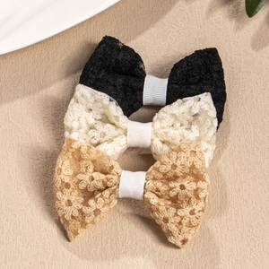 Close-up of three lace floral embroidered bow hair clips in black, cream and beige gold