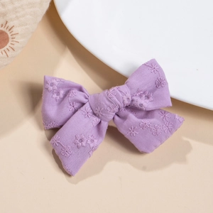 Close-up of handmade purple cotton hair clip with elegant white floral embroidery