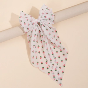 Close-up of strawberry print chiffon bow hair clip with elegant long ribbons on a stand