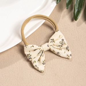 Detailed view of baby headband with floral bow and high elastic nylon band on beige background