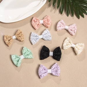 Overview of eight colorful lace bow hair clips for girls displayed on beach sand decor