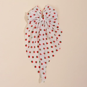 Detailed view of white strawberry floral bow hair clip with long elegant ribbons