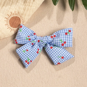 Close-up of blue plaid bow with cherry print on a beach sand background