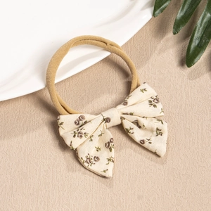 Close-up of floral fabric bow headband with brown nylon elastic band for infants