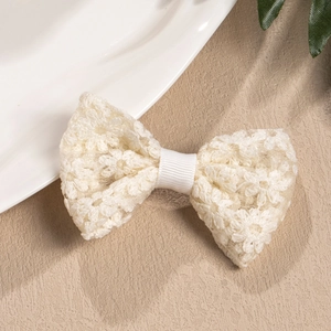 Detail of white crochet lace bow hair clip featuring intricate floral embroidery textures