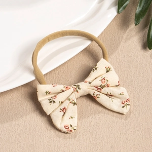 Close-up of baby nylon headband with floral cotton bow and natural aesthetic