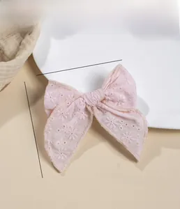 Détail de la barrette à nœud rose clair avec broderie florale blanche en coton doux