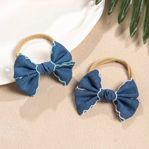 Detail of blue denim baby bow headband with white wave stitching and soft nylon band
