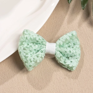 Detail of mint green lace bow hair clip with embroidered floral textures and ribbed center