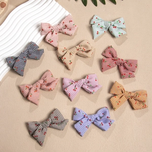 Set of colorful plaid bow hair clips with cherry prints for girls on a white display board