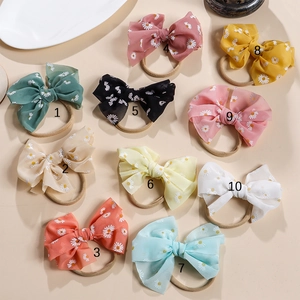 Flache Ansicht von 10 bunten Baby-Stirnbändern mit Gänseblümchen-Muster und Nylon-Gummiband