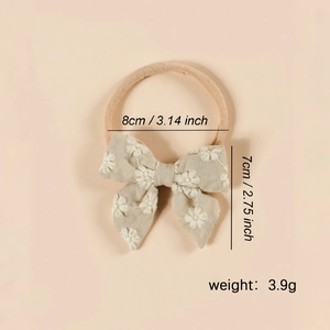 Détail d'un bandeau bébé beige avec broderie florale et dimensions affichées