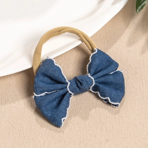 Close-up of blue denim bow headband with white embroidery on a soft nylon elastic band