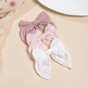 Détail de nœuds en coton avec broderie florale et ajourages de trois couleurs variées