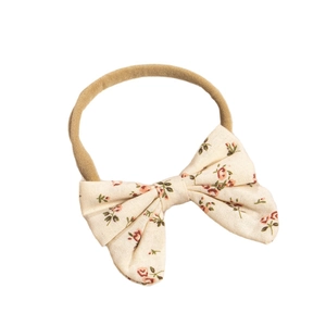 Floral bow baby headband with red rose pattern and elastic nylon band on white background
