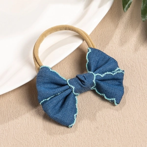 Detailed view of handmade navy bow headband with blue stitching and nude nylon band