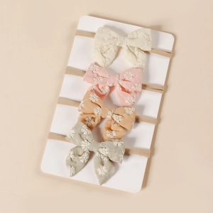 Détail de quatre bandeaux bébé en nylon avec nœuds floraux brodés aux couleurs pastel