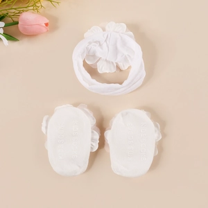 Detailed view of white baby headband with floral design and matching lace socks