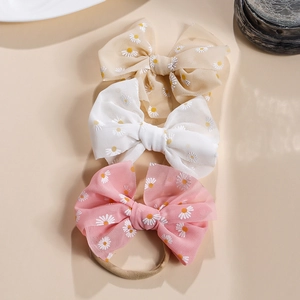 Detailaufnahme von drei Baby-Stirnbändern mit Gänseblümchenmuster in Pastellfarben
