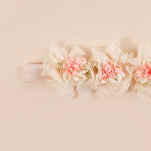 Detail of baby headband with three layers of chiffon flowers and green ribbon leaves