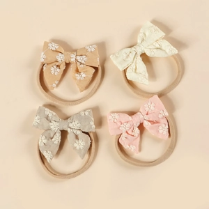 Détail de quatre bandeaux bébé en nylon souple avec des nœuds brodés de fleurs