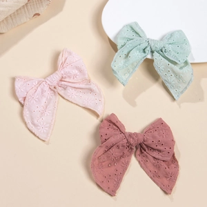 Détail de trois nœuds à cheveux en coton brodé en rose pastel et vert menthe