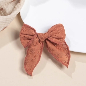 Détail d'un nœud papillon en coton orange rouille avec broderie florale ajourée délicate