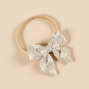 Détail du bandeau bébé en nylon avec noeud en coton et broderie de marguerites
