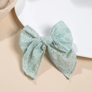 Détail du nœud à cheveux en coton vert menthe avec broderie florale ajourée