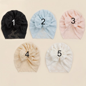 Flat lay of five infant lace bow turbans in black, blue, pink, beige, and cream colors