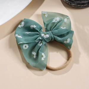 Detailansicht der grünen Haarschleife mit Gänseblümchen-Print und elastischem Nylonband