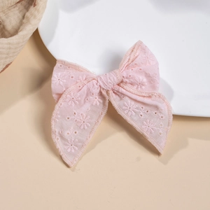 Détail d'un nœud papillon en coton rose avec broderie florale et bords surpiqués sur l'assiette