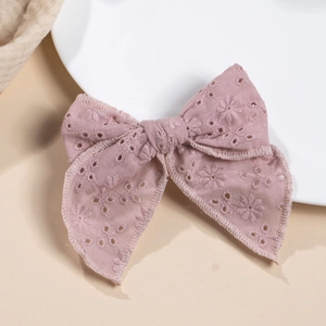 Détail du nœud à cheveux rose-violet avec broderie ajourée et texture coton douce