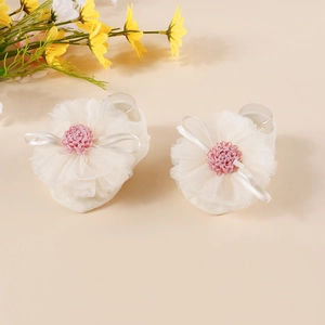 Detail of baby soft knit shoe with layered white mesh flowers and pink fabric floral centers