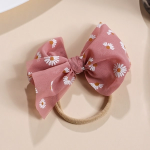 Detailaufnahme einer rosa Netzschleife mit Gänseblümchen-Muster auf einem beigen Nylon-Stirnband