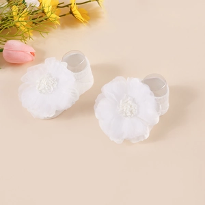Close-up of white baby sock with delicate organza flower and fine stitching detail