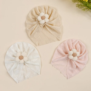 Close-up of delicate lace floral baby turbans in beige, white and soft pink colors