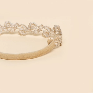 Détail d'une fleur en dentelle argentée scintillante sur un bandeau élastique bébé