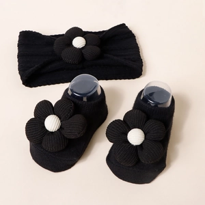 Detailed view of the soft knitted texture and 3D floral accents on infant headband and socks