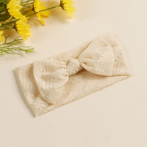 Détail d'un bandeau pour bébé en dentelle beige avec broderie florale et grand nœud