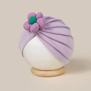 Gros plan détaillé d'un bonnet turban violet pour bébé avec une fleur 3D décorative