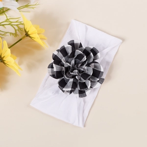 Detail of baby headband with elastic white fabric and a 3D black and white checkered flower