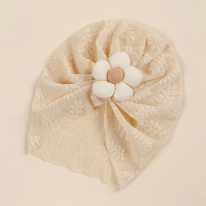 Close-up of beige lace infant turban with large white corduroy flower detail