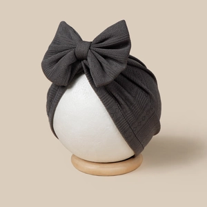 Detail view of dark grey baby turban with large bow and ribbed knit texture on a head model